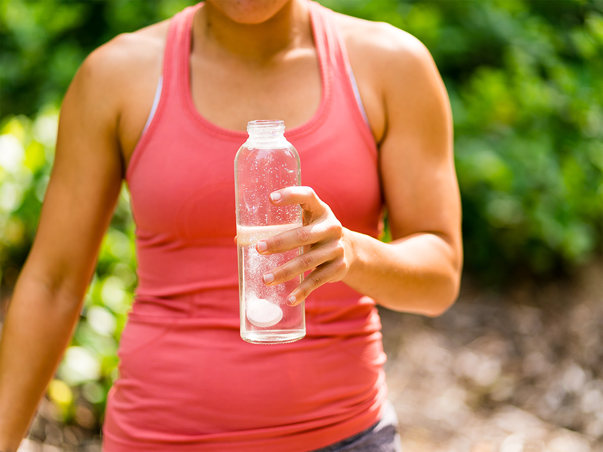 Person holding a waterbottle with a Nuun tablet dissolving in water