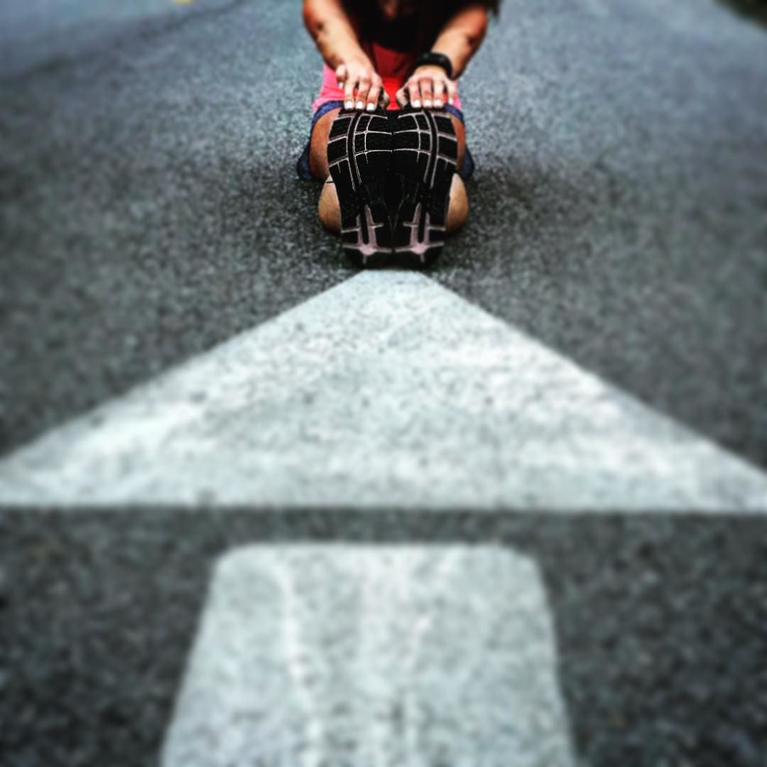 Person reaching for their toes by an arrow painted on the road