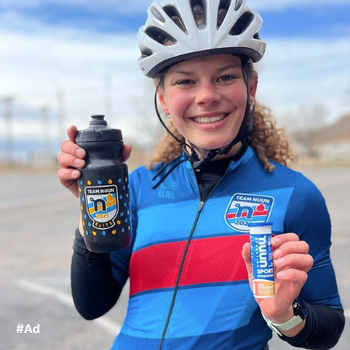 A bicycler holding a tube of Nuun Sport and a Nuun Branded water bottle